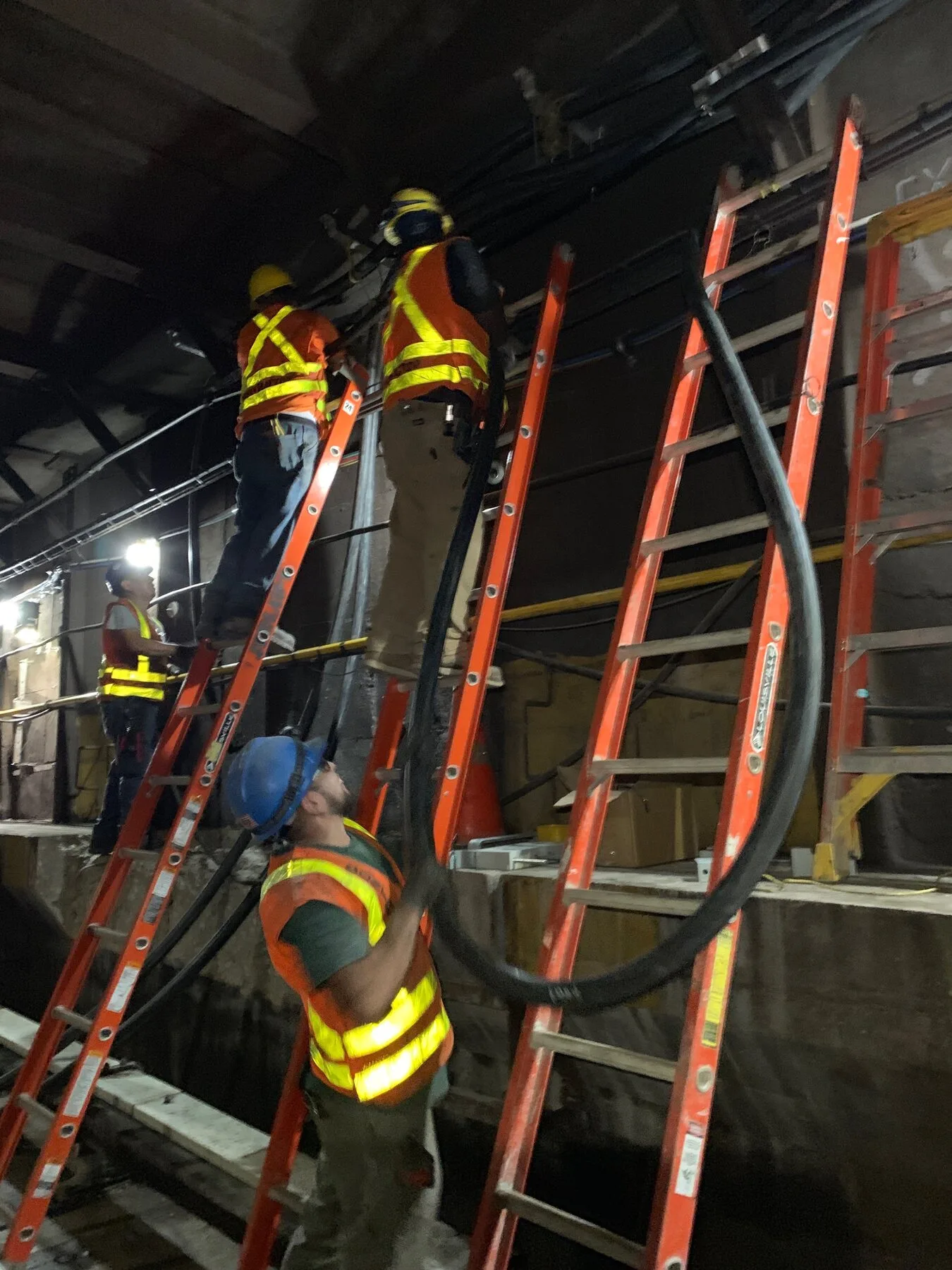 Electricians working from ladders inside a rail tunnel